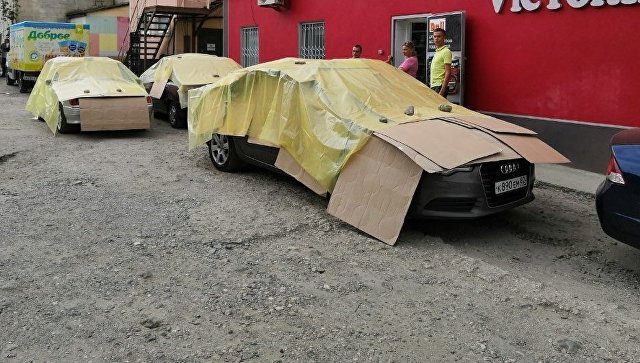 Фотофакт: крымчане прячут авто от града под щитами из одеял, досок и ковров